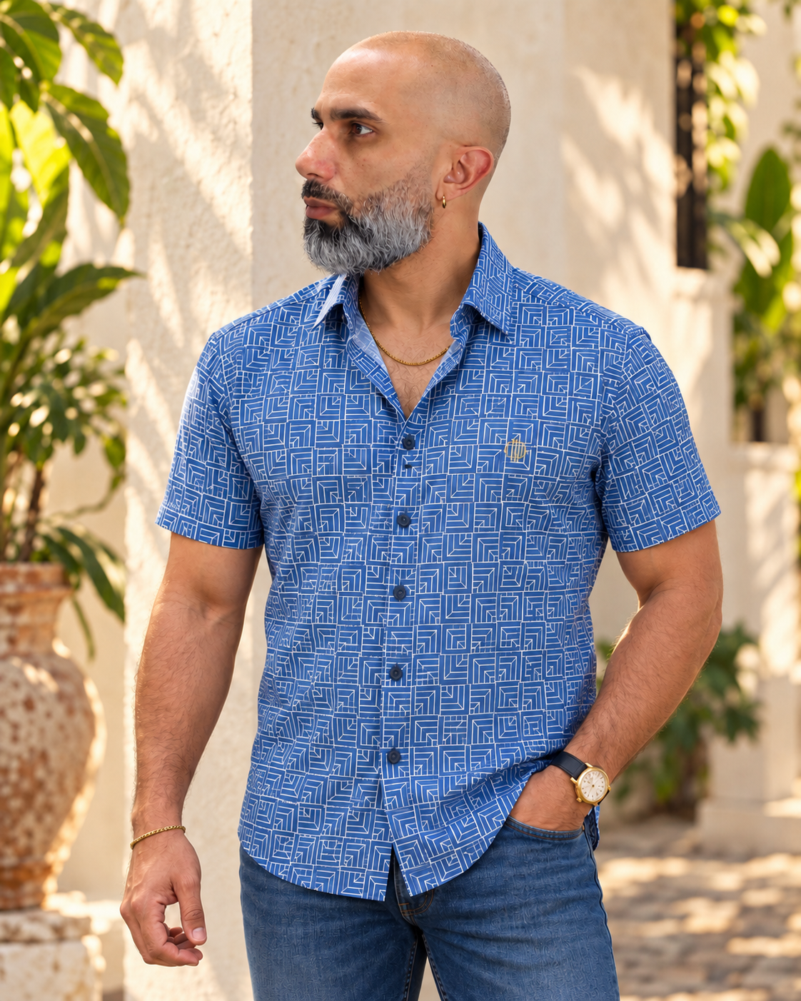 Modelo con camisa MW Twilight azul geométrica en ambiente tropical junto a una fachada